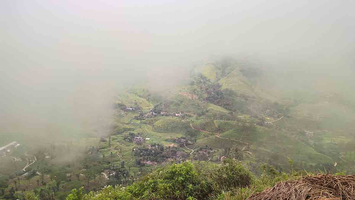 Aerial cliff-edge view from Kalabokka 360 over a misty valley and village below