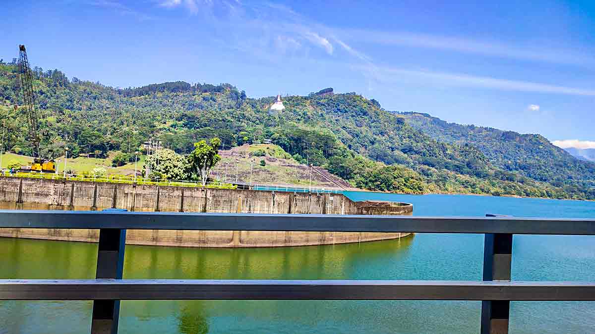 View from Kotmale Reservoir observation point showing dam spillway and white Buddhist stupa on the hillside