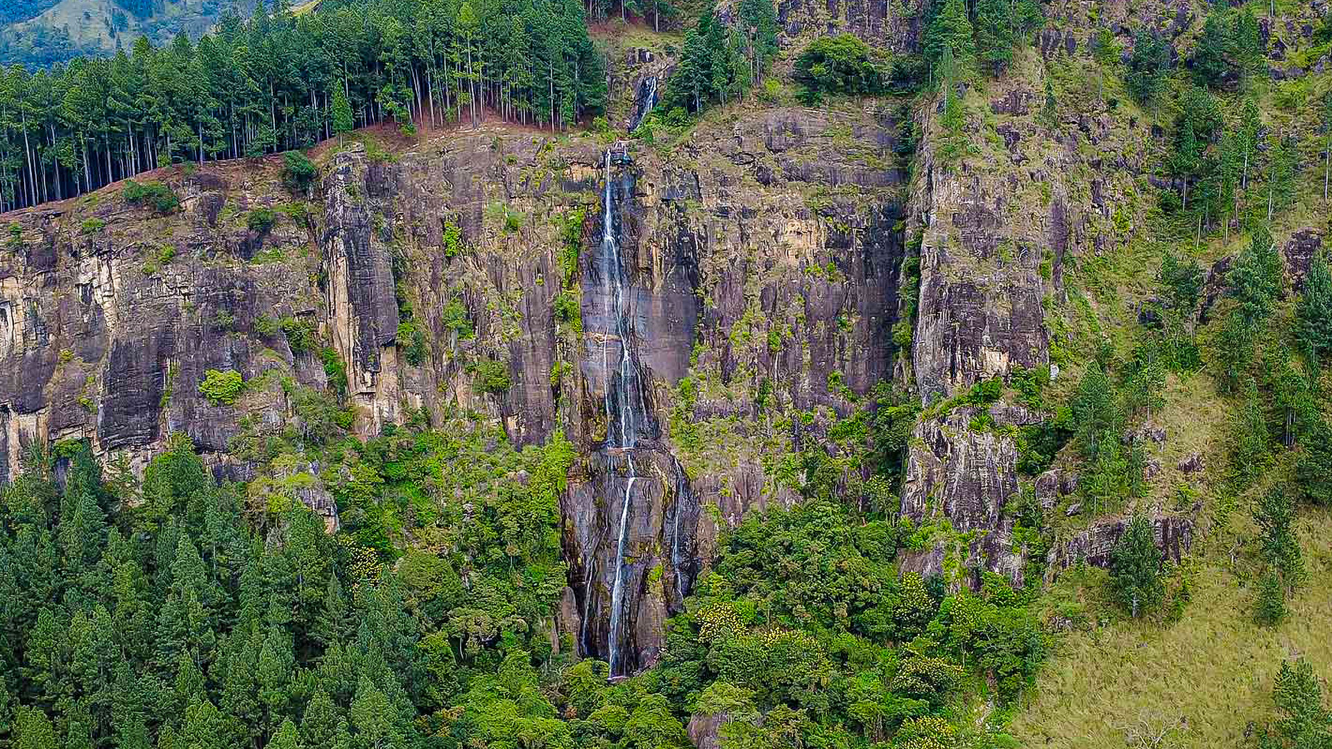 A tall waterfall surrounded by dense tropical forest